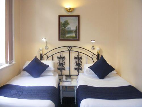 伦敦美人鱼套房酒店的两张位于酒店客房的床,配有蓝色枕头