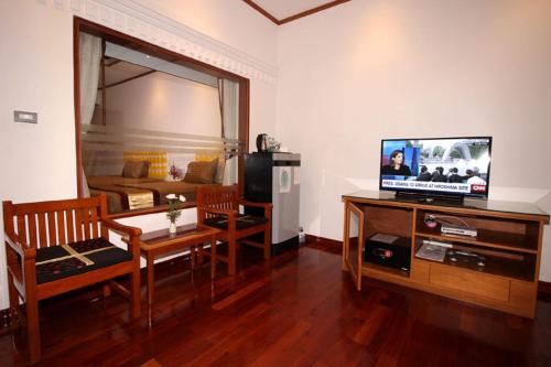 仰光缅甸生活酒店的客厅配有电视和桌椅