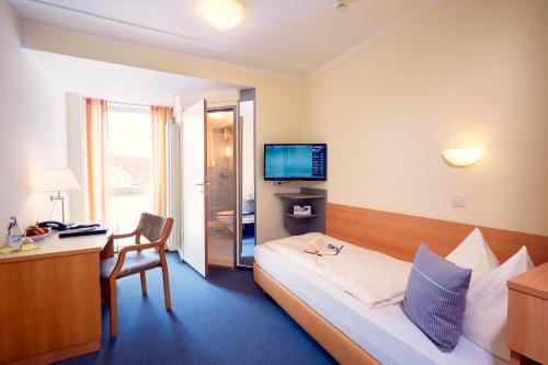 帕德博恩IN VIA Hotel的酒店客房配有一张床、一张书桌和一台电视。