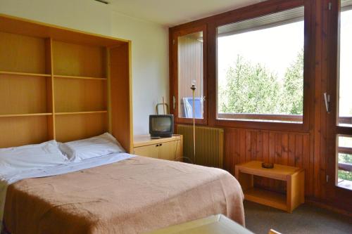 布勒伊-切尔维尼亚Appartamenti La Maison de Vacances的一间卧室设有一张床、一台电视和一个窗口。