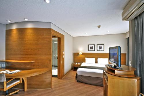 圣保罗保利斯塔行政全美酒店的配有一张床和一张书桌的酒店客房