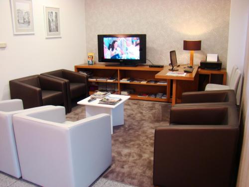 波尔图斯库洛酒店的客厅配有椅子、电视和桌子