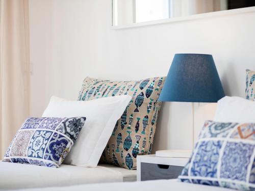 里斯本Marino Lisboa Boutique Guest House的一张带蓝色和白色枕头的床和一盏灯