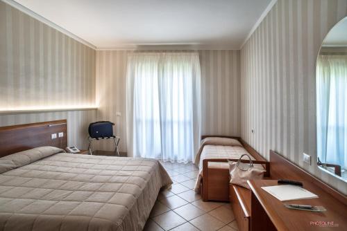 钱皮诺茱莉亚别墅酒店的酒店客房设有两张床、一张桌子和一面镜子