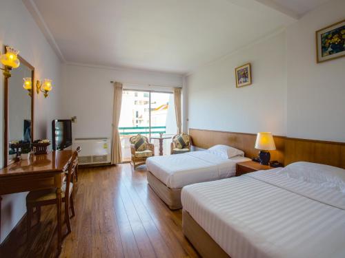 华欣华欣斯里酒店的酒店客房设有两张床、一张桌子和一台电视。