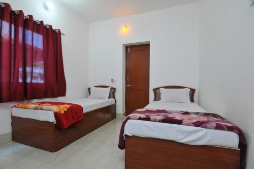 菩提伽耶拉玛旅馆的配有红色窗帘的客房内的两张床
