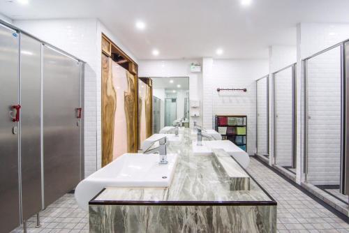 芭堤雅市中心浓泽旅馆的浴室设有3个水槽和一排镜子