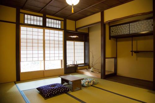 京都无限酒店的一间设有桌子、两个窗户和长凳的房间