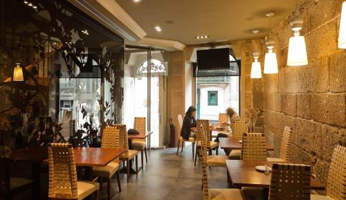 维戈普埃塔甘博亚酒店的一间设有桌椅的餐厅,以及一位背景人士