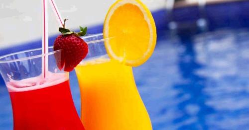 桑托斯阿兰蒂科金色公寓酒店的一杯饮料,配上草莓和橘子片,在游泳池旁边