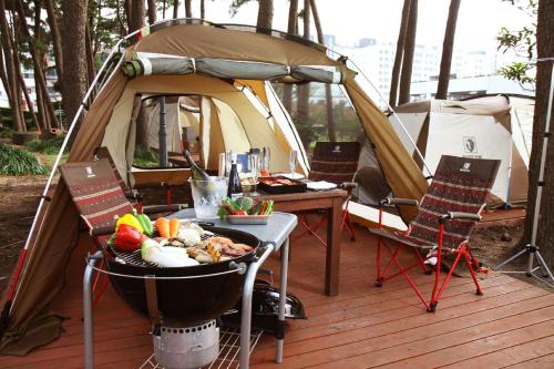 济州市济州岛梅生格拉德酒店的一个带烧烤架的帐篷和一张带食物的桌子