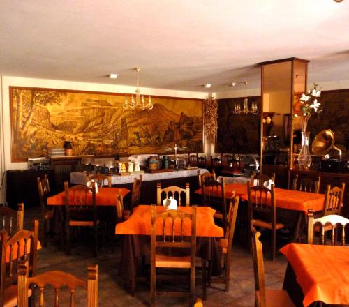 托尔拉雪绒花酒店的餐厅设有桌椅,墙上挂着一幅大画