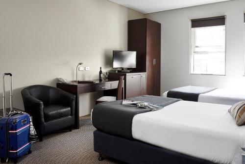 悉尼Vulcan Hotel Sydney的酒店客房配有一张床、一张桌子和一把椅子。