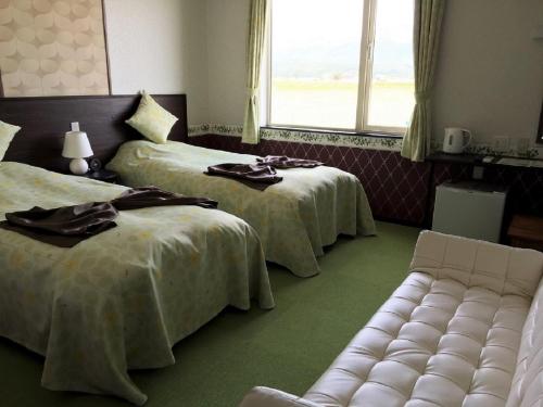中富良野町布兰科芙蓉佩蒂特酒店的客房设有两张床、一张沙发和一个窗口。