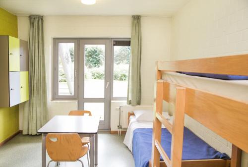 布鲁日欧罗巴旅舍的一间卧室配有两张双层床、一张桌子和一张书桌。