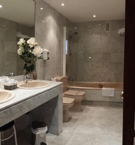 萨拉曼卡圣保罗酒店的浴室配有2个盥洗盆、卫生间和浴缸。