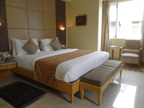 孟买Ascot Hotel的酒店客房带一张大床和一把椅子