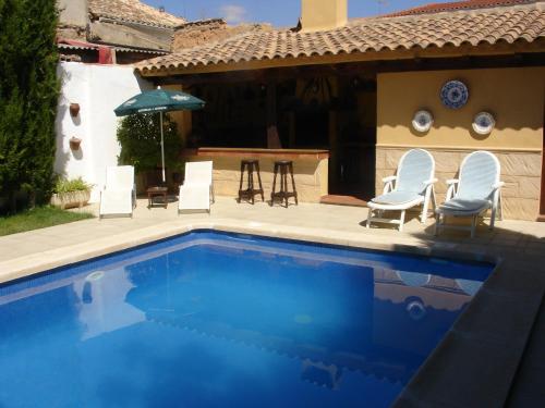MotillejaCasa rural Villa Parchis的一个带椅子和桌子的游泳池以及一把遮阳伞