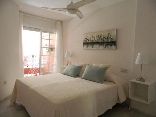 马拉加Apartamento Miramar的卧室配有白色的床和吊扇