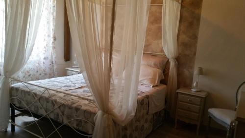 Badia a RuotiCasa Romina的卧室配有带白色窗帘的天蓬床