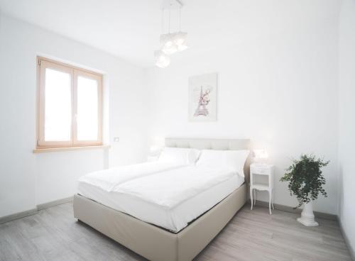 加尔达湖滨Appartamenti Ora e Peler的白色的卧室设有白色的床和窗户。