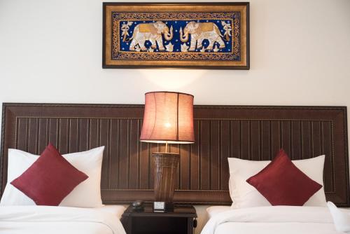 曼谷True Siam Rangnam Hotel的酒店客房设有两张床,墙上挂着一张照片。