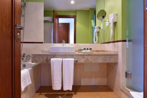 圣多美佩斯塔纳圣多美酒店的一间带水槽、浴缸和镜子的浴室