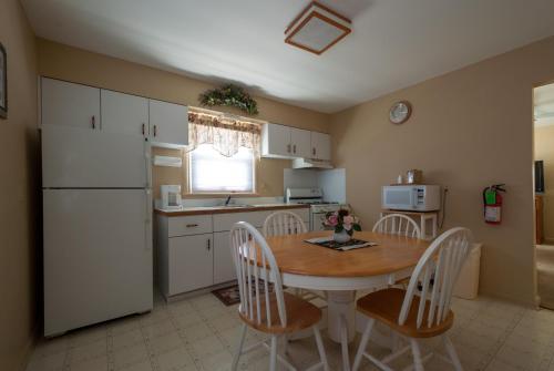 波因特普莱森特海滩Point Pleasant Manor的厨房配有桌椅和白色冰箱。