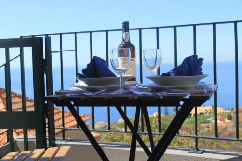 Venda do AtalhinhoMaison Zita的阳台上的桌子上摆放着玻璃杯和一瓶葡萄酒