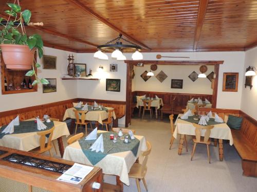 巴特奥塞斯陶德威尔特酒店的用餐室设有桌椅和木制天花板
