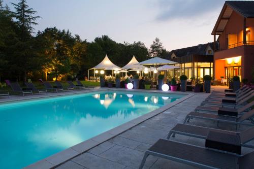 Dracy-le-Fort德拉西温泉酒店的游泳池在晚上提供椅子和遮阳伞