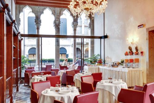 威尼斯多纳宫酒店的一间带桌椅和吊灯的用餐室