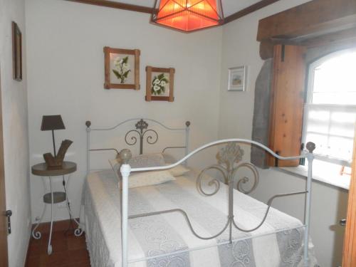 FeteiraCasa Ilhéu - Fajã do Fisher的一间卧室配有一张床、一张桌子和一个窗户。