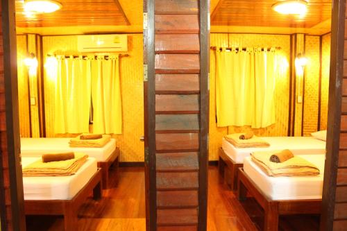 安帕瓦Baansuan Lychee Maeklong Resort Ampawa的带3张床和黄色窗帘的房间