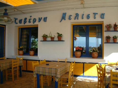 马拉希亚斯Melistas Rooms的餐厅墙上挂有桌椅和植物