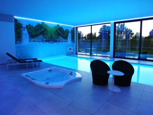 于瑟尔B&B Vita Roka met extra Luxe Privé Wellness的一个带浴缸和椅子的大型游泳池