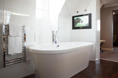 海斯廷斯班纳坦温泉酒店的带浴缸的白色浴室以及墙上的电视。
