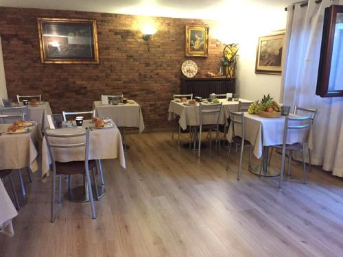 佩罗Relais Villa Rosa的一间设有白色桌椅的餐厅,拥有砖墙