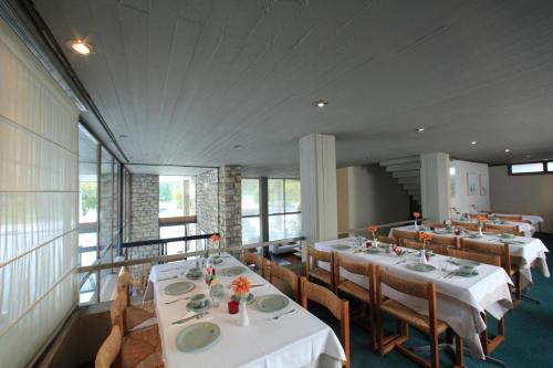 斯巴达蒂斯克里酒店的一间设有白色桌椅和窗户的用餐室
