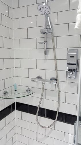 海维康雷克特酒店 的白色瓷砖浴室内带软管的淋浴
