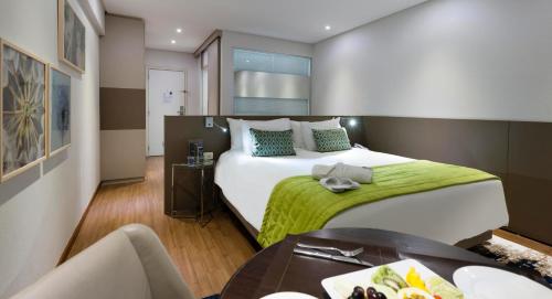 戈亚尼亚Comfort Suites Flamboyant Goiânia的酒店客房设有一张大床和一张桌子。