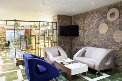 萨姆松内巴皇家酒店的大堂设有两把椅子、一张桌子和一台电视。