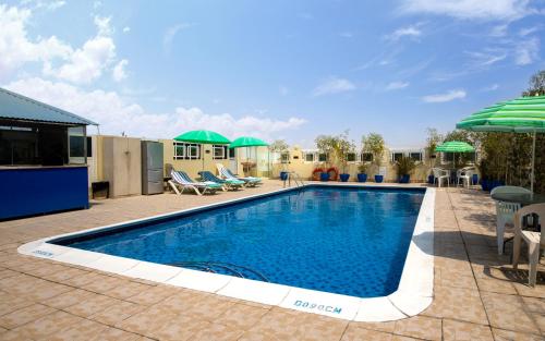 迪拜Benta Grand Hotel LLC的庭院内一个带椅子和遮阳伞的游泳池