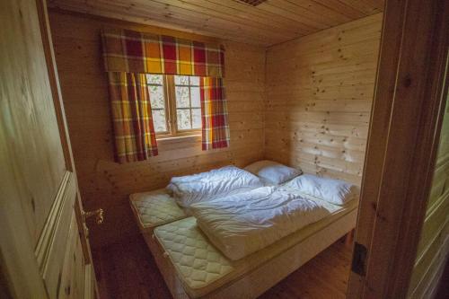 ViksdalenStrandbu的木制客房的一张小床,设有窗户