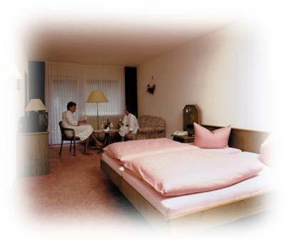 Grasellenbach博格瓦尔道酒店的卧室配有一张床,而人坐在桌子上