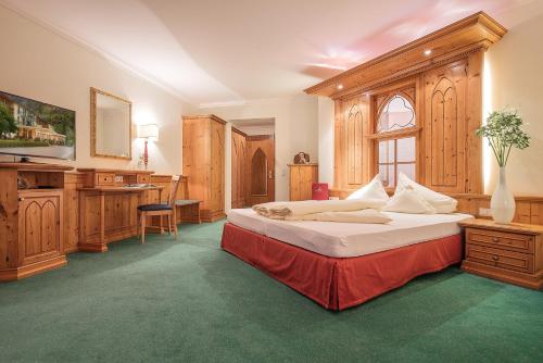 施伦斯Hotel Vitalquelle Montafon的一间卧室配有一张大床和一张书桌