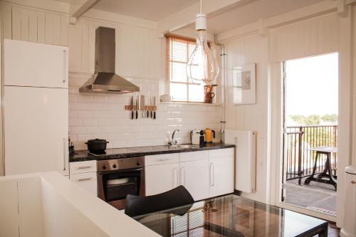 哈林亨Het Dakhuis的厨房配有白色橱柜和炉灶烤箱。