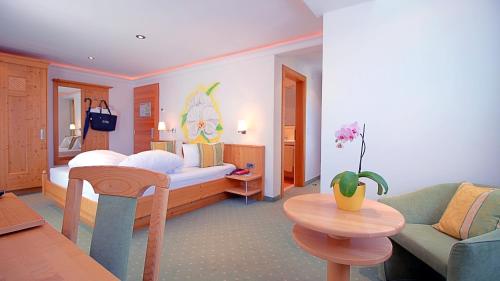 萨姆瑙恩Samnaunerhof Vital-Hotel的一间卧室配有一张床、一张沙发和一张桌子