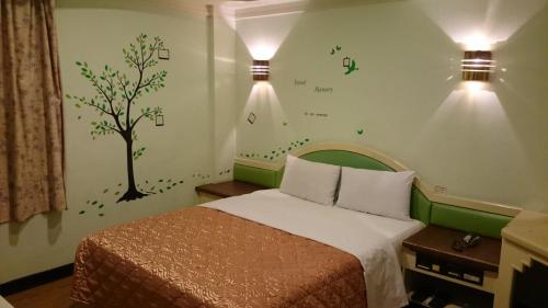台中市丽都平价商务旅馆的卧室配有一张墙壁上涂有树的床铺。
