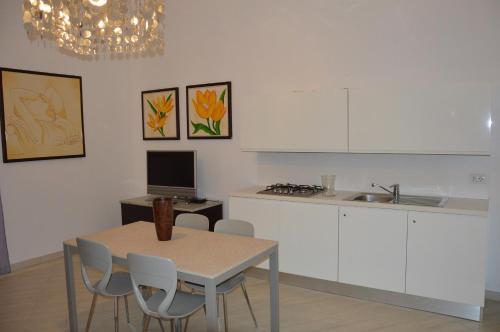 马萨夫拉Ancora Una Volta的厨房配有桌子、白色橱柜和桌椅